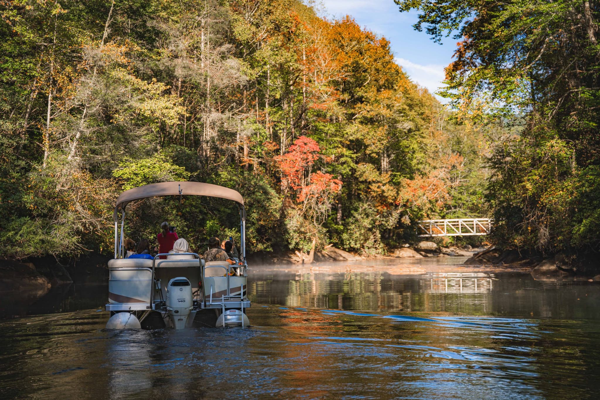 Pontoon navigating a fall cove on Lake Jocassee